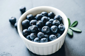 Fresh blueberries in bowl on concrete background. Selective focus