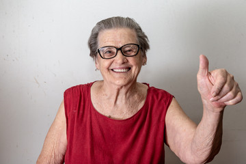 Beautiful old woman with two tumbs up. Cheerful caucasian senior showing two thumbs up on white...