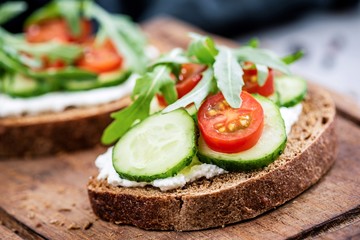 Healthy food rye bread with cream cheese, cucumber, tomato and arugula. Closeup view