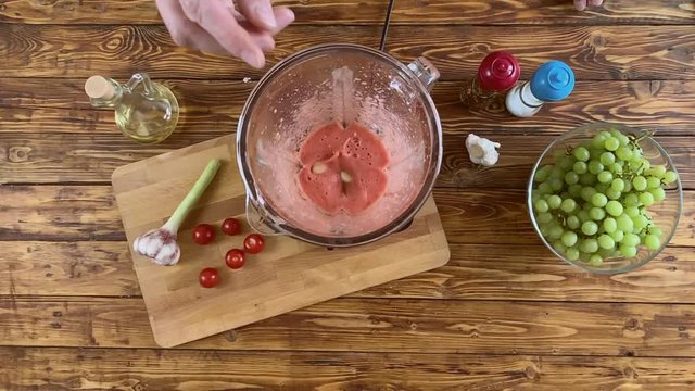 Woman is putting garlic to blender