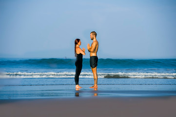 young attractive and beautiful acrobat couple practicing acroyoga exercise concentrated keeping balance practiing yoga on the beach in relaxation and meditation concept