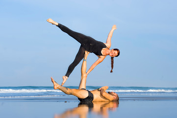 young attractive and beautiful acrobat couple practicing acroyoga exercise concentrated keeping...