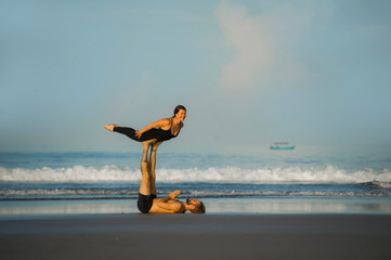 young attractive and beautiful acrobat couple practicing acroyoga exercise concentrated keeping...