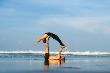 young attractive and beautiful acrobat couple practicing acroyoga exercise concentrated keeping...