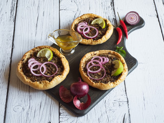 Arabian opened meat pies Sfiha on wooden board.
