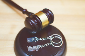 Judge gavel and key ring in shape of two splitted part of house on wooden background. Concept of...