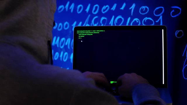 Hacker in dark room writing programming code or using virus program for cyber attack. Programmer Developer hacking or writes the source code of the software.