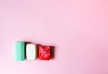 Different colorful soap bars on soft pink background