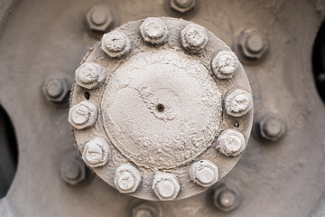 The hub of the rear wheel of the bus or a large machine with bolts and nuts, covered with road mud sand and salt mixture  Dirty wheel of the bus wheel hub bearing in the daylight