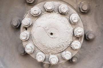 The hub of the rear wheel of the bus or a large machine with bolts and nuts, covered with road mud sand and salt mixture  Dirty wheel of the bus wheel hub bearing in the daylight
