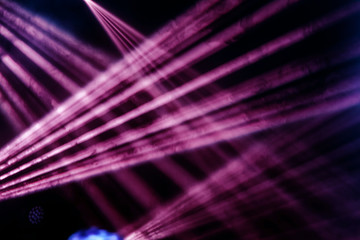 Stage lights. Several projectors in the dark. Multi-colored light beams from the stage spotlights on the stage in the smoke at the time of the entertainment show. Night club. Lights show. Lazer show