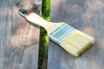 A wide paint brush lies on a wooden Board on the green grass in the street close-up. Paint brush ...