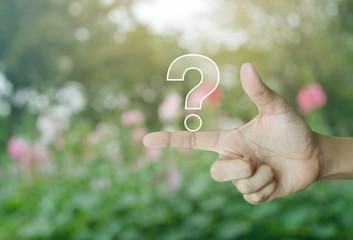 Question mark sign icon on finger over blur pink flower and tree in park, Business customer service and support concept