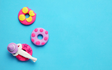 Plasticine people relaxing on inflatable donut lilo in pool. Cartoon summer relaxing and holidays.