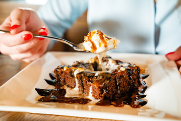 woman eating brownie with ice cream and caramel