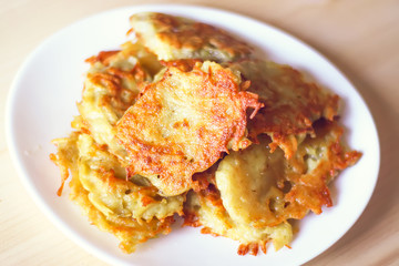 Homemade potato pancakes in a white plate on a wooden table