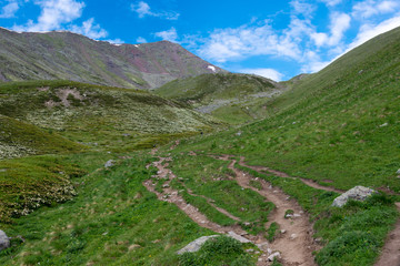 Fototapeta na wymiar Kazbegi, Georgia - Jun 29 2018: Mountain range on a hiking trail from Gergeti Trinity Church to Gergeti Glacier. a famous landscape in Kazbegi, Mtskheta-Mtianeti, Georgia.