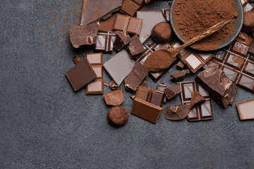 Dark or milk organic chocolate pieces, cocoa powder and truffle candies on dark concrete backgound