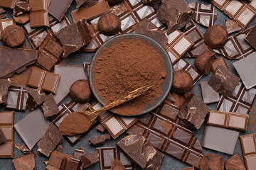 Dark or milk organic chocolate pieces, cocoa powder and truffle candies on dark concrete backgound