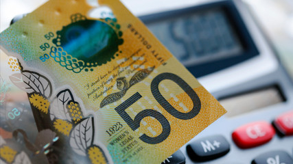 Australian fifty dollar bill over a calculator. The new 2019 issue is designed to deter...