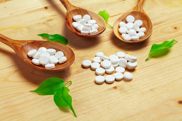Medicine capsules, pills on wooden spoon background