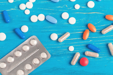 Many different pills on dark blue wooden background