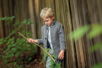 bully boy stands by a fence with a wooden stick