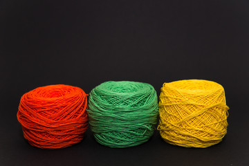 colored knitting yarn and hooks on a black background with space for text