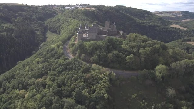 Approaching above Bourscheid castle in Luxembourg. Showing the surrounding mountains, forests and village in the back. Sunny weather with clouds.