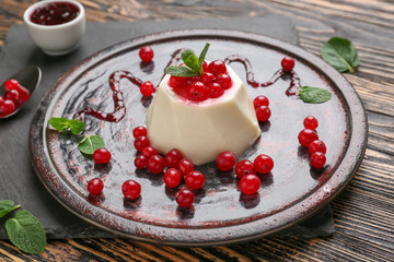 Plate with tasty panna cotta on wooden table