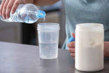 Sporty man making protein shake at home, closeup