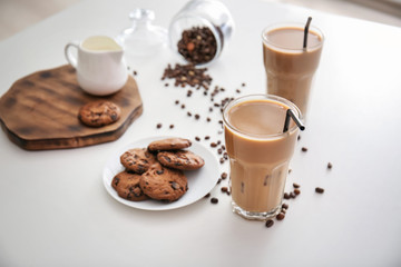 Glasses of tasty frappe coffee with cookies on white table