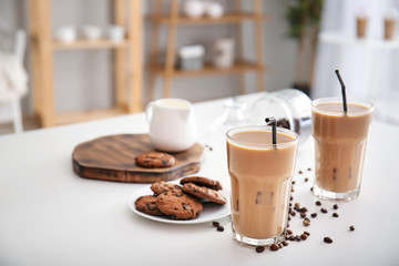 Glasses of tasty frappe coffee with cookies on white table