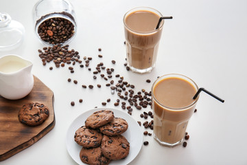 Glasses of tasty frappe coffee with cookies on white table