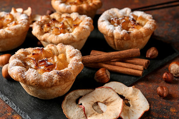 Slate plate with tasty apple pies on table