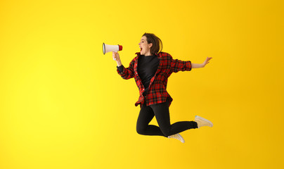 Jumping young woman with megaphone against color background