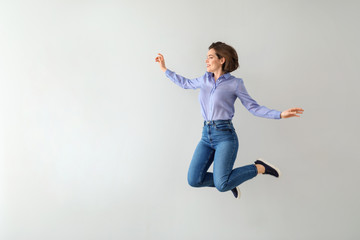 Jumping young woman against light background