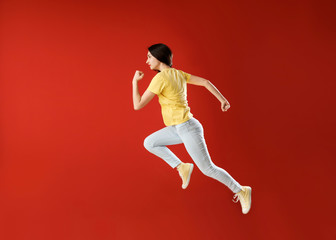 Fototapeta na wymiar Running young woman against color background
