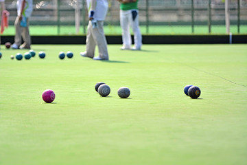 Ladies playing lawn bowls. Soft focus on the green blurred background