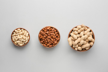 Bowls with tasty peanuts on light background
