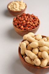 Bowls with tasty peanuts on light background