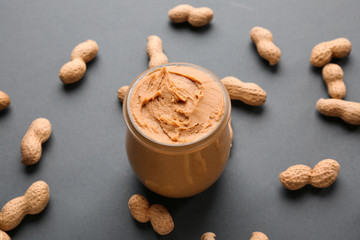 Jar with tasty peanut butter on dark background