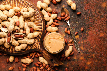 Board with tasty peanut butter and nuts on color background