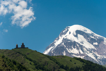 Obraz premium Kazbegi, Georgia - Jun 30 2018: Mount Kazbek at Gergeti Trinity Church. a famous landscape in Kazbegi, Mtskheta-Mtianeti, Georgia.