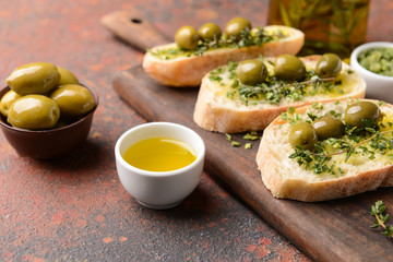 Slices of bread with olives, oil and herbs on table
