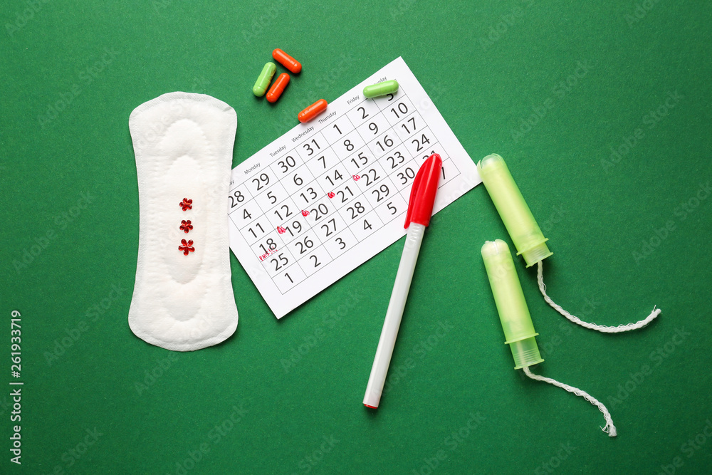 Wall mural menstrual calendar with feminine products and pills on color background