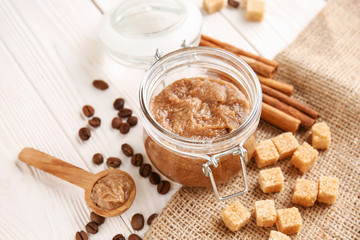 Jar with sugar scrub and ingredients on white table