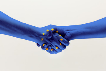 Cooperation agreement. Male hands shaking colored in blue EU flag isolated on gray studio...
