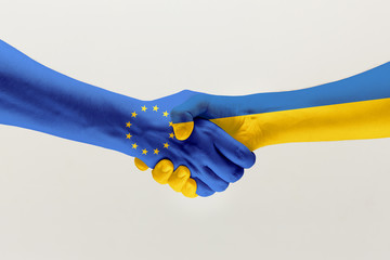 Welcome gesture. Two male hands shaking colored in flag of European Unity and Ukraine isolated on...
