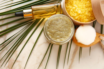 Jar with sugar scrub and cosmetic products on light table